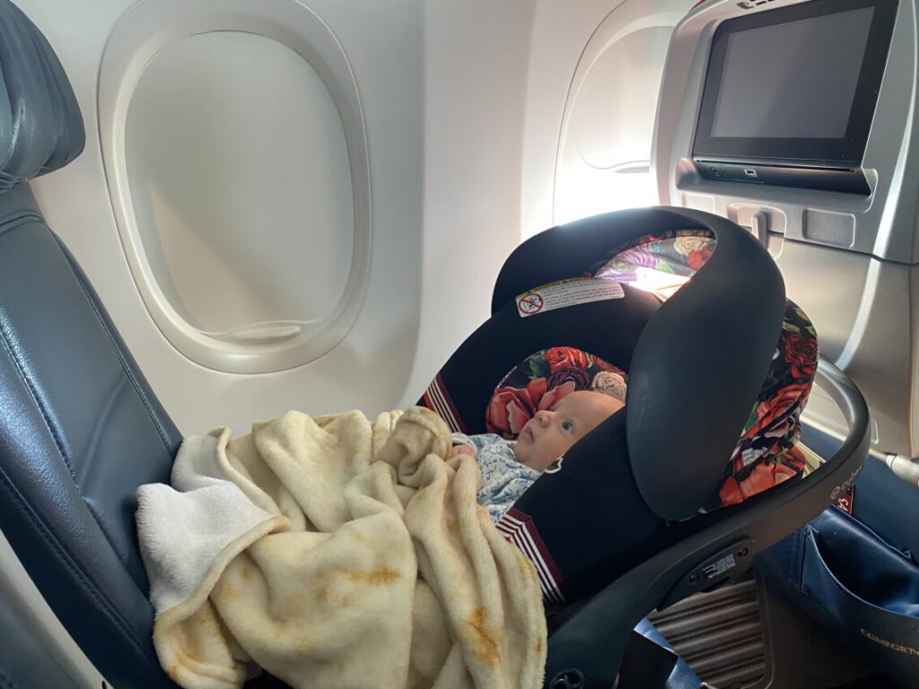 a child in a car seat on plane